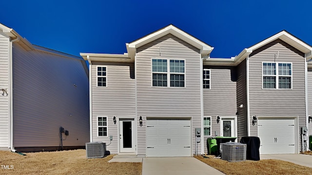 view of property featuring cooling unit, a garage, and driveway