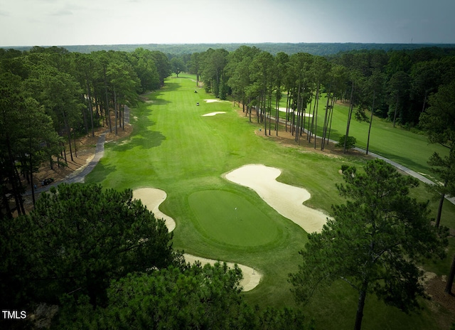 view of property's community with view of golf course and a wooded view