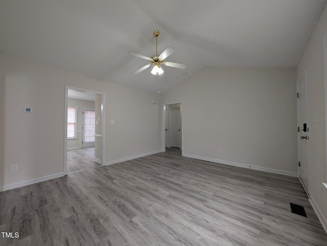 empty room featuring ceiling fan, visible vents, wood finished floors, and vaulted ceiling