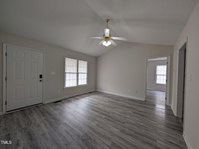 unfurnished living room with vaulted ceiling, a textured ceiling, baseboards, and wood finished floors