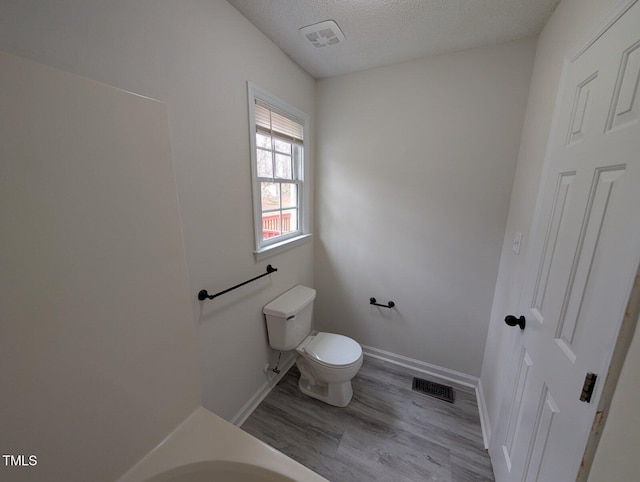 bathroom with visible vents, a textured ceiling, toilet, and wood finished floors