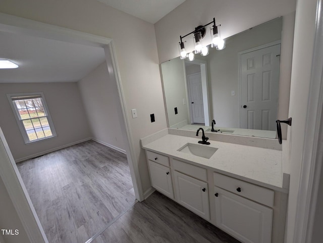 bathroom featuring baseboards, wood finished floors, and vanity