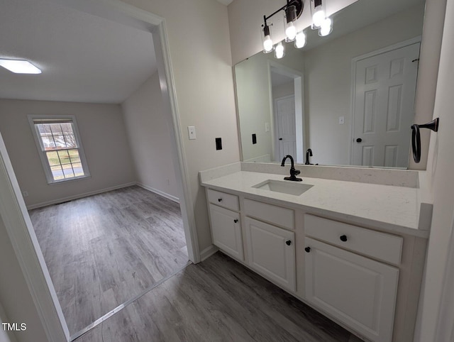 bathroom with vanity, wood finished floors, and baseboards