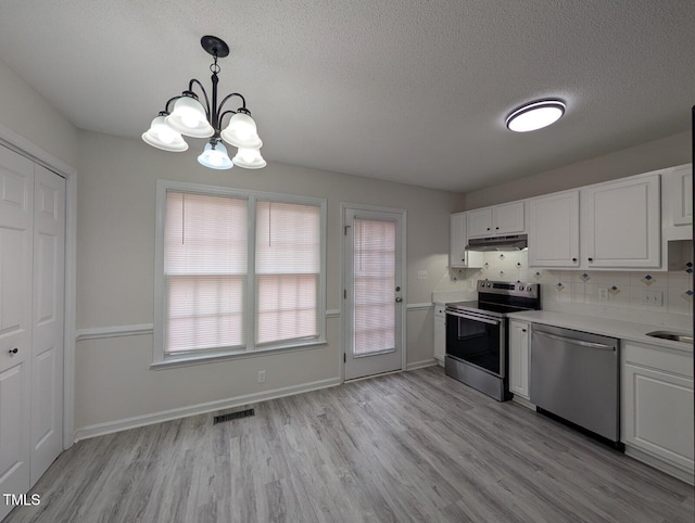 kitchen featuring light wood-type flooring, visible vents, under cabinet range hood, stainless steel appliances, and light countertops