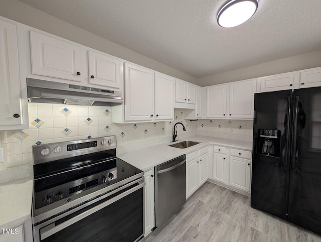 kitchen with under cabinet range hood, appliances with stainless steel finishes, light countertops, and a sink