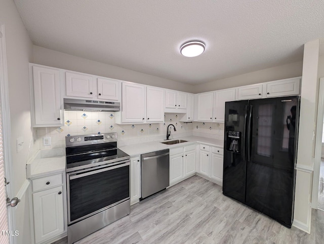 kitchen with a sink, stainless steel appliances, light countertops, under cabinet range hood, and white cabinetry