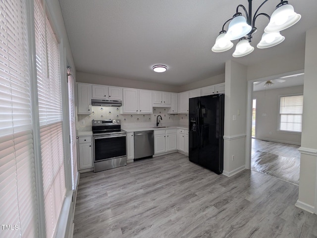 kitchen featuring a sink, tasteful backsplash, ventilation hood, stainless steel appliances, and light countertops