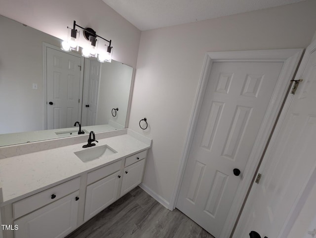 bathroom with baseboards, wood finished floors, and vanity