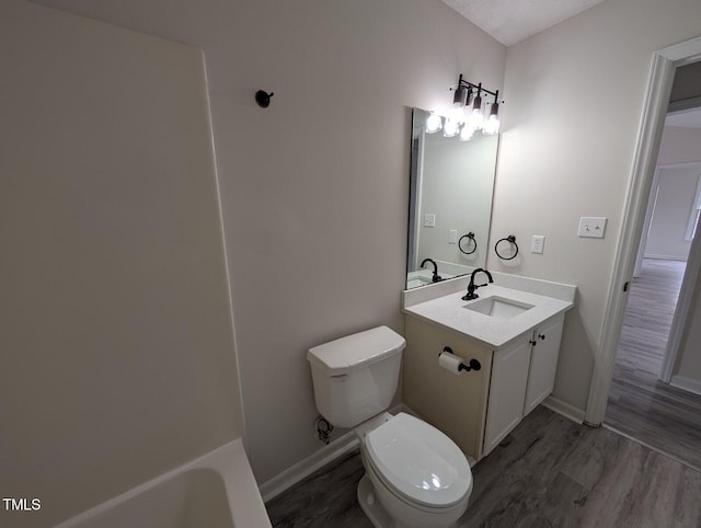 bathroom with baseboards, toilet, wood finished floors, and vanity