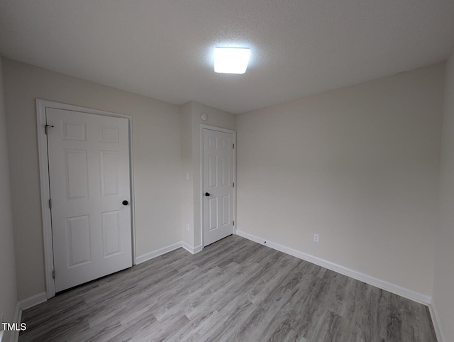 unfurnished bedroom with baseboards, a textured ceiling, and wood finished floors