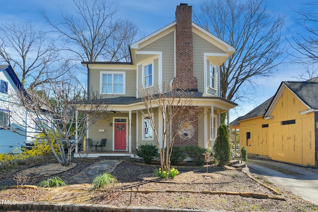 view of front of house with brick siding, covered porch, and a chimney