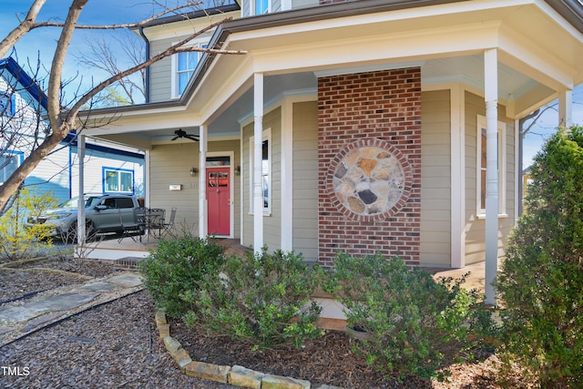 property entrance with brick siding, covered porch, and ceiling fan