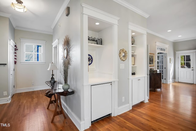 corridor with a healthy amount of sunlight, ornamental molding, and wood finished floors