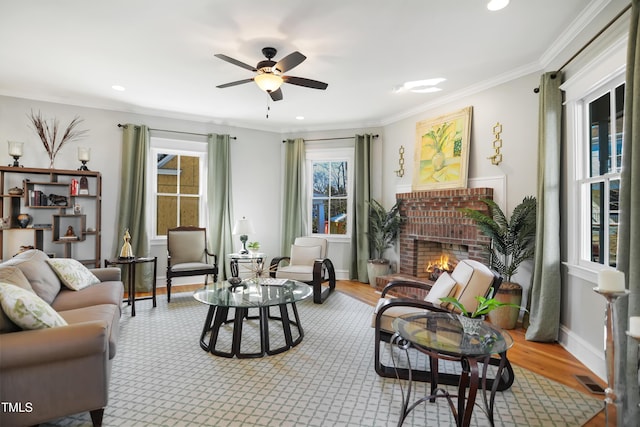 living area with wood finished floors, plenty of natural light, a brick fireplace, and ornamental molding