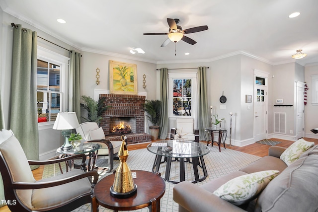 living area featuring visible vents, ornamental molding, wood finished floors, a fireplace, and baseboards