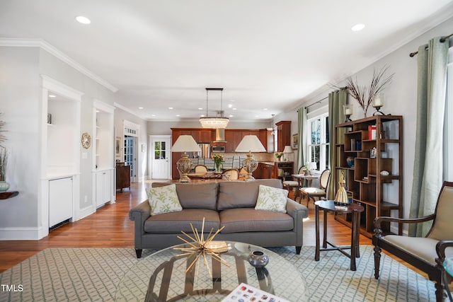 living room with recessed lighting, wood finished floors, baseboards, and ornamental molding