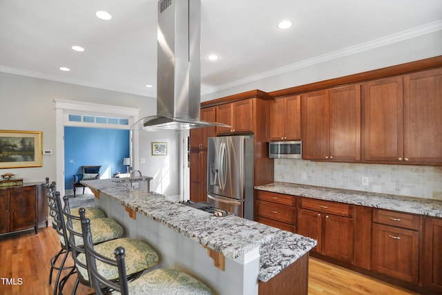 kitchen with stainless steel appliances, light wood-style floors, a breakfast bar, and island range hood