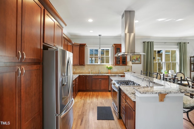 kitchen featuring tasteful backsplash, stainless steel appliances, a breakfast bar area, island range hood, and glass insert cabinets