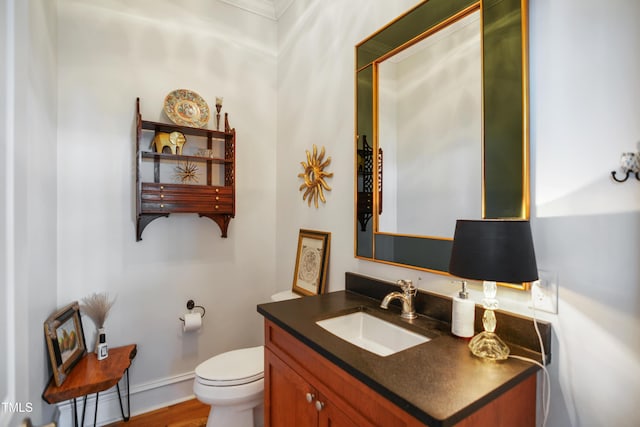 bathroom featuring vanity, toilet, wood finished floors, and baseboards