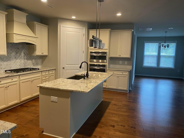 kitchen featuring dark wood-type flooring, premium range hood, stainless steel appliances, white cabinetry, and a sink