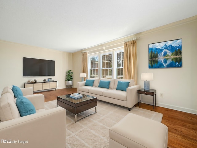 living area with light wood-style flooring, crown molding, and baseboards