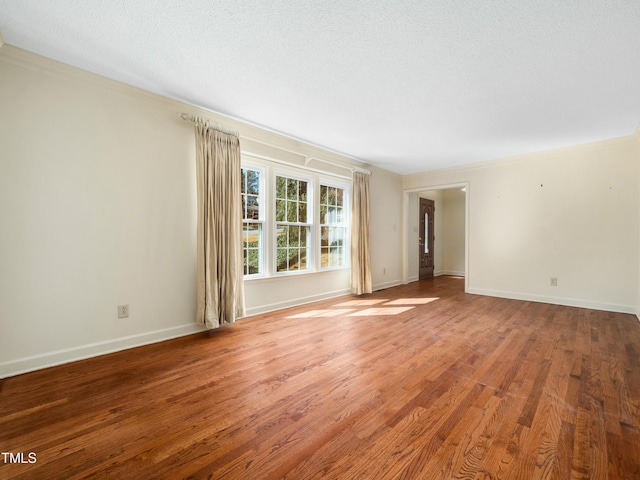 unfurnished room featuring baseboards, a textured ceiling, wood finished floors, and crown molding