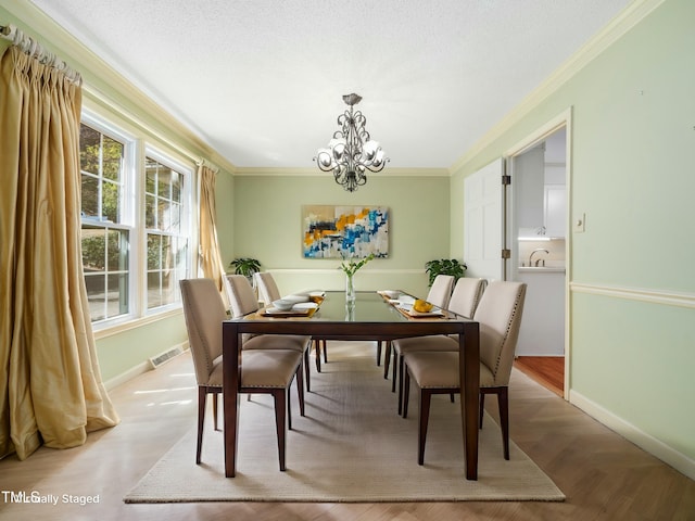 dining space with visible vents, baseboards, a chandelier, and ornamental molding