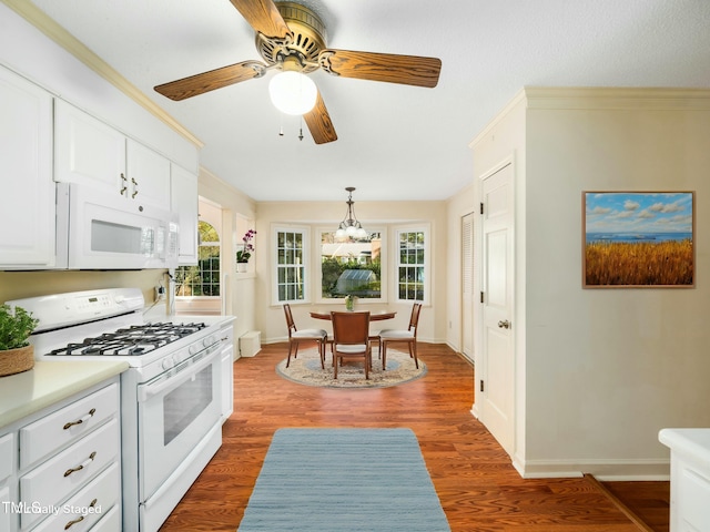 kitchen with white appliances, wood finished floors, ceiling fan, light countertops, and white cabinets