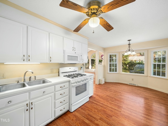 kitchen with white appliances, plenty of natural light, light wood-style floors, and a sink