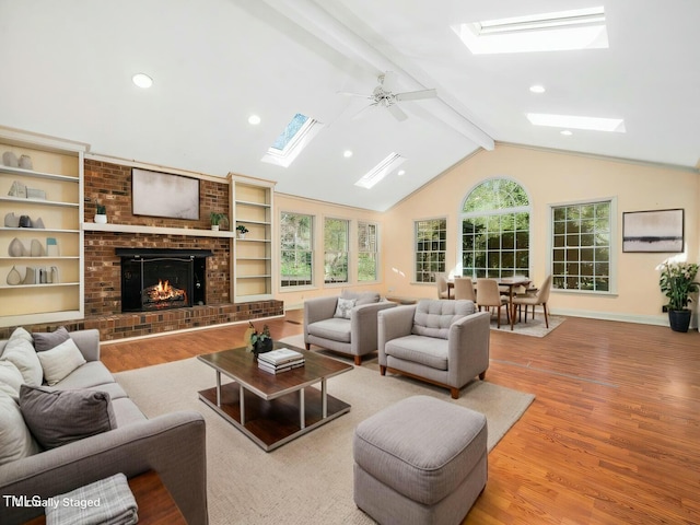 living area with baseboards, recessed lighting, vaulted ceiling with skylight, a fireplace, and wood finished floors