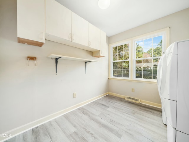 unfurnished room with light wood-type flooring, visible vents, baseboards, and washer / dryer