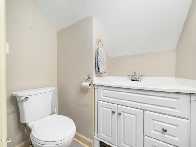 bathroom featuring baseboards, toilet, vanity, and vaulted ceiling