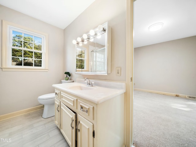 bathroom featuring walk in shower, toilet, vanity, and baseboards