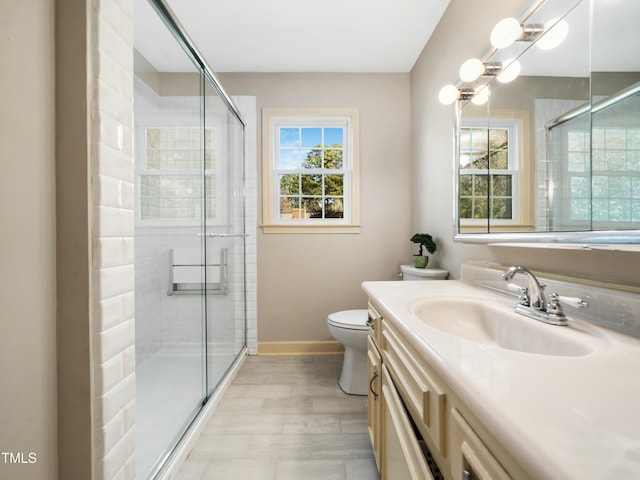 bathroom with baseboards, vanity, toilet, and a shower stall