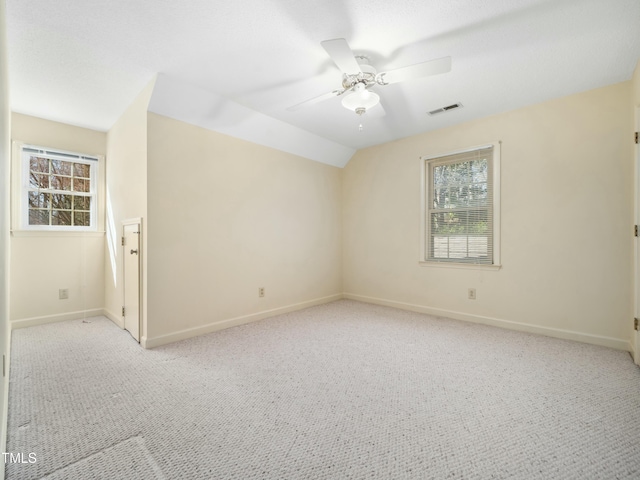 unfurnished room with lofted ceiling, carpet flooring, visible vents, and ceiling fan