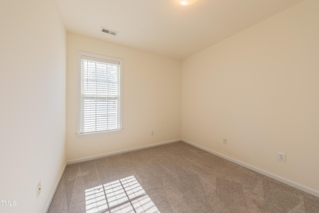 spare room with visible vents, carpet, and baseboards