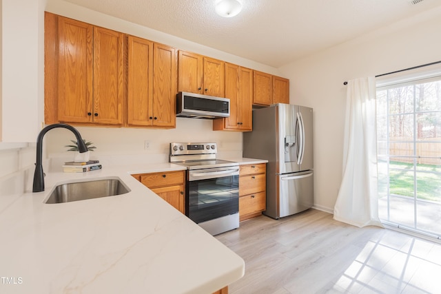 kitchen featuring a sink, plenty of natural light, appliances with stainless steel finishes, and brown cabinetry