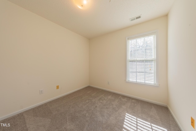 empty room featuring baseboards, visible vents, carpet floors, and a textured ceiling