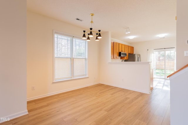 interior space with baseboards, light wood-type flooring, and an inviting chandelier