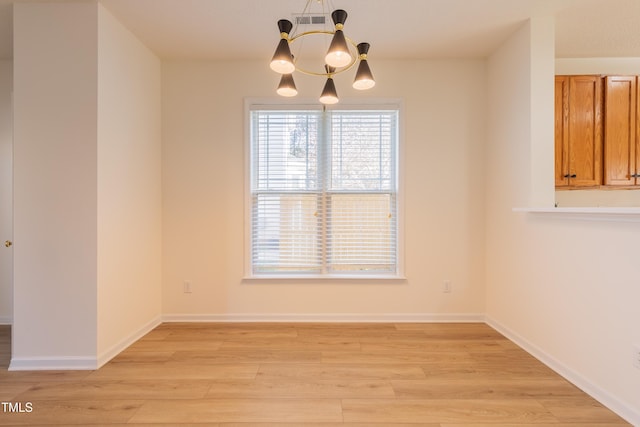 unfurnished dining area with visible vents, baseboards, a chandelier, and light wood finished floors