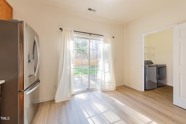 unfurnished dining area with light wood-type flooring, baseboards, visible vents, and independent washer and dryer