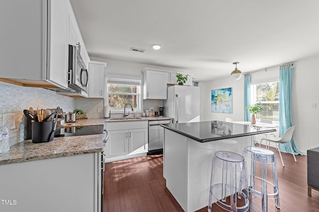 kitchen featuring a breakfast bar, decorative backsplash, dark wood-style flooring, and appliances with stainless steel finishes