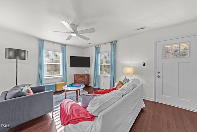 living room with visible vents, dark wood-type flooring, and a ceiling fan