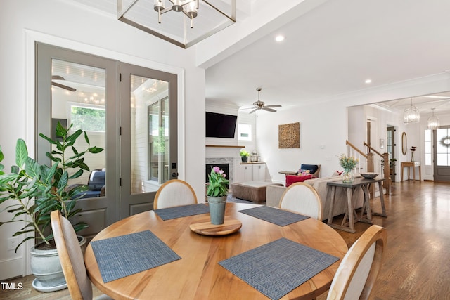 3337 Cheswick Dr, Raleigh, NC 27609 - dining area featuring a chandelier, wood finished floors, a ceiling fan, a fireplace, and crown molding