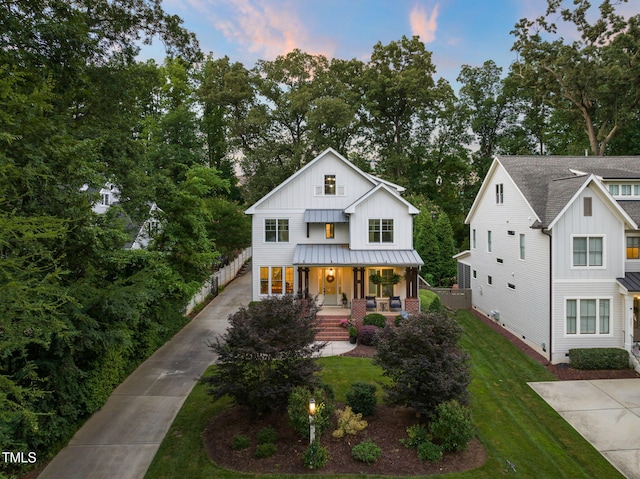 3337 Cheswick Dr, Raleigh, NC 27609 - modern inspired farmhouse featuring a porch, board and batten siding, a standing seam roof, and a front lawn