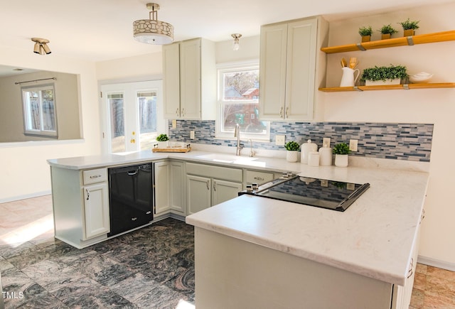 kitchen featuring a peninsula, stovetop, a sink, decorative backsplash, and dishwasher