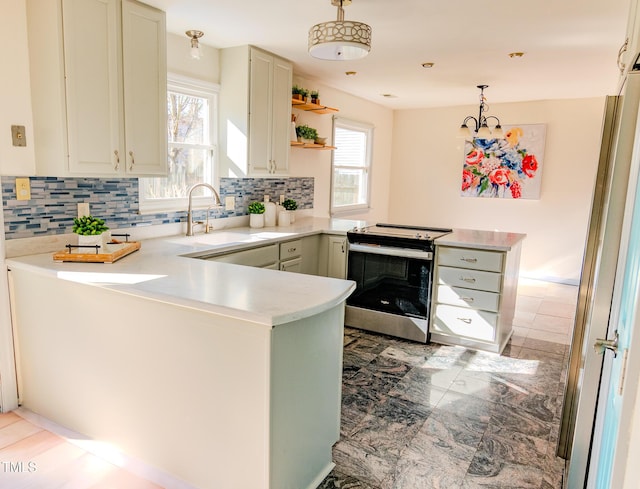 kitchen with a peninsula, electric range, light countertops, and a sink