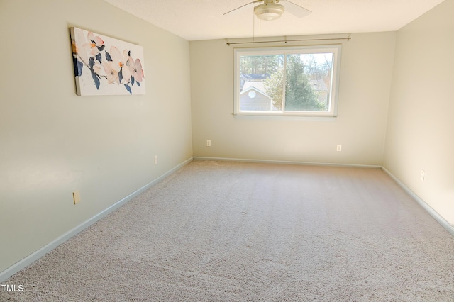 carpeted empty room with a ceiling fan and baseboards