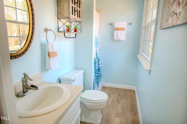 bathroom featuring vanity, a shower with shower curtain, wood finished floors, baseboards, and toilet