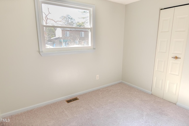 empty room featuring visible vents, baseboards, and carpet